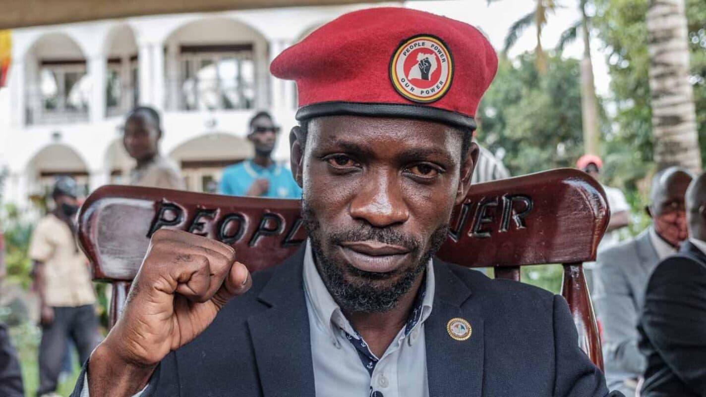 Ugandan opposition leader Bobi Wine raising a fist while seated in a chair marked 'People Power'