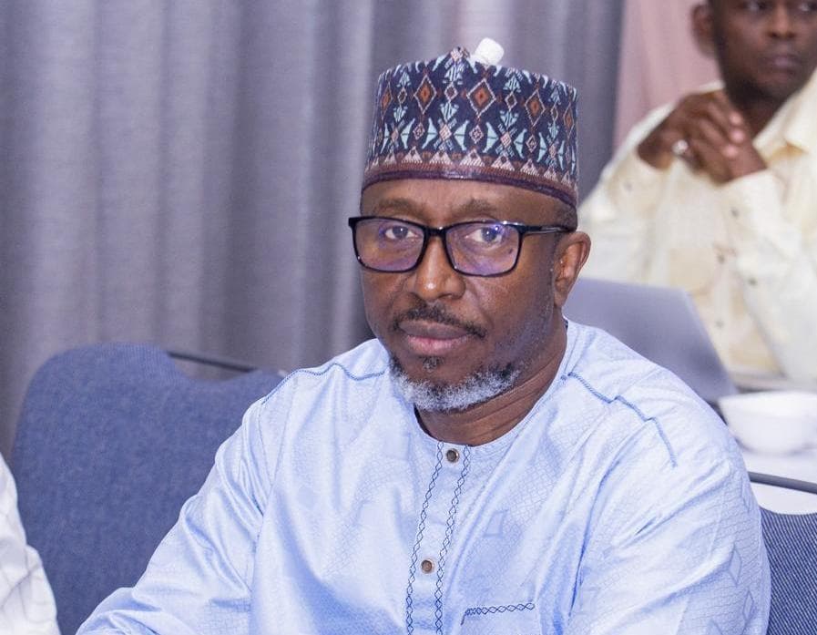 ECOWAS Parliament member Dr. Suleiman Gumi seated at a meeting wearing glasses and a traditional cap