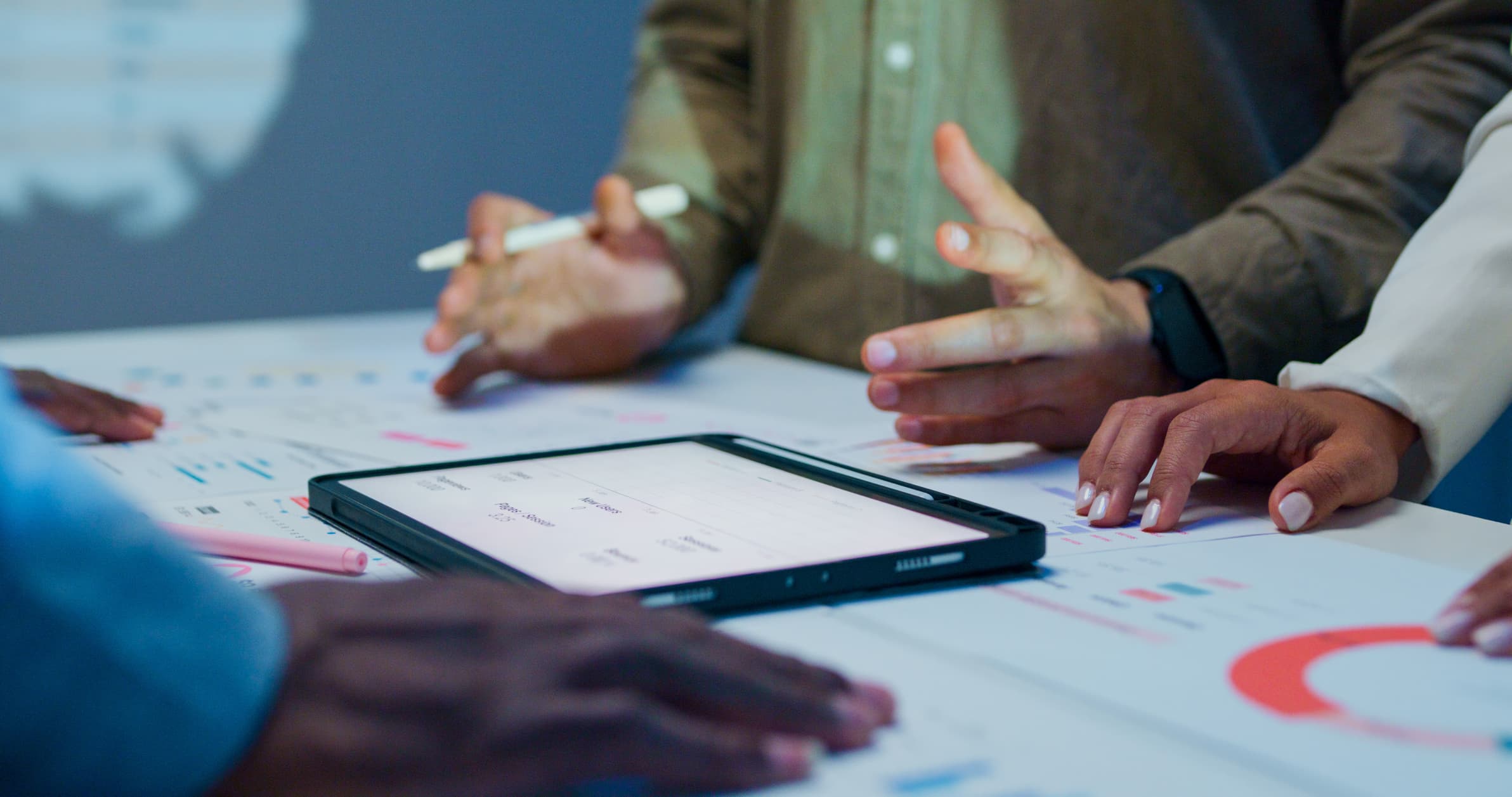 Business professionals analyzing financial charts and reports on a digital tablet during a late-night meeting