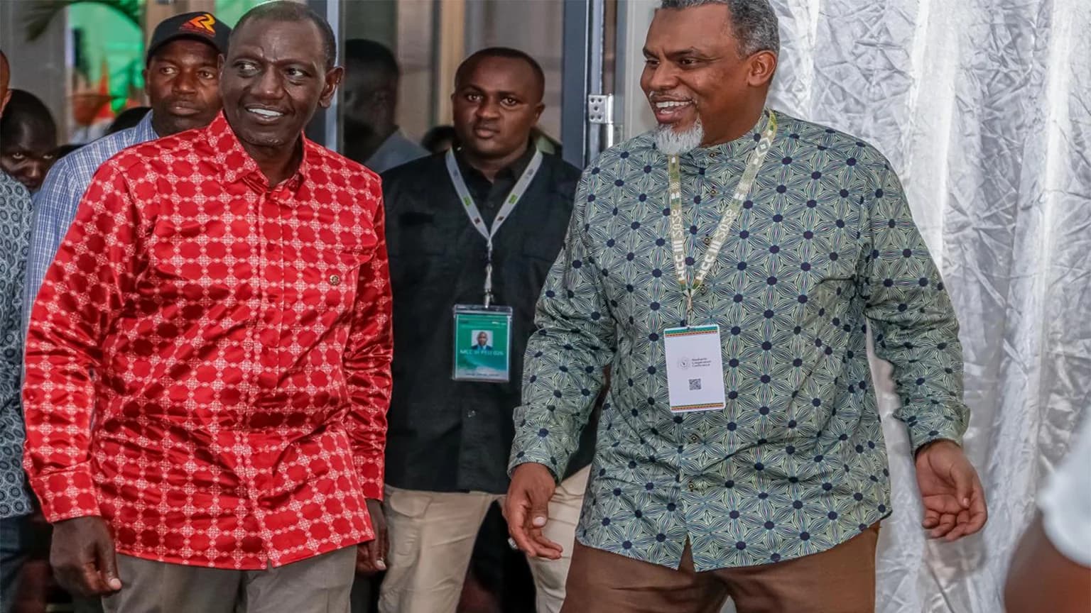 Kenyan President William Ruto walking alongside another official at a conference venue