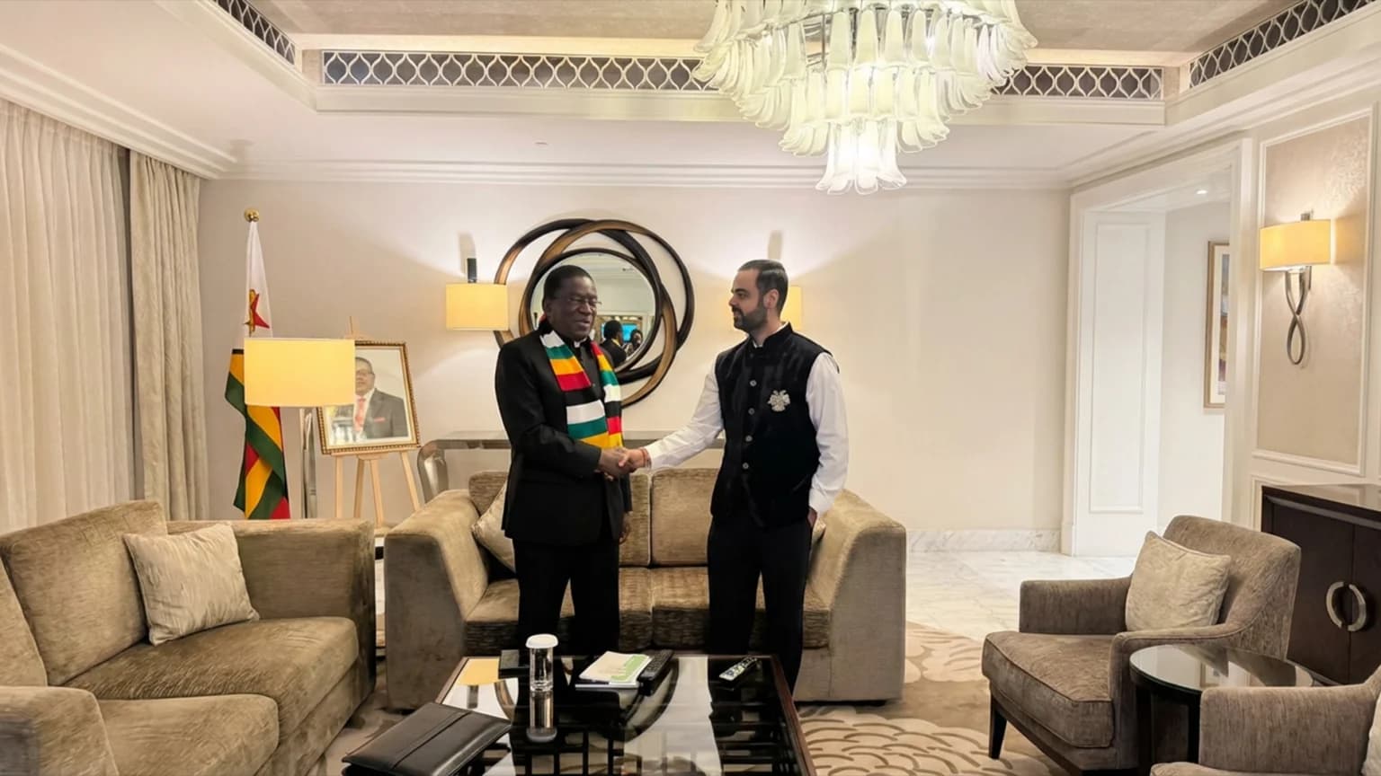 Zimbabwean President Emmerson Mnangagwa shaking hands with investor Prateek Suri in a hotel suite