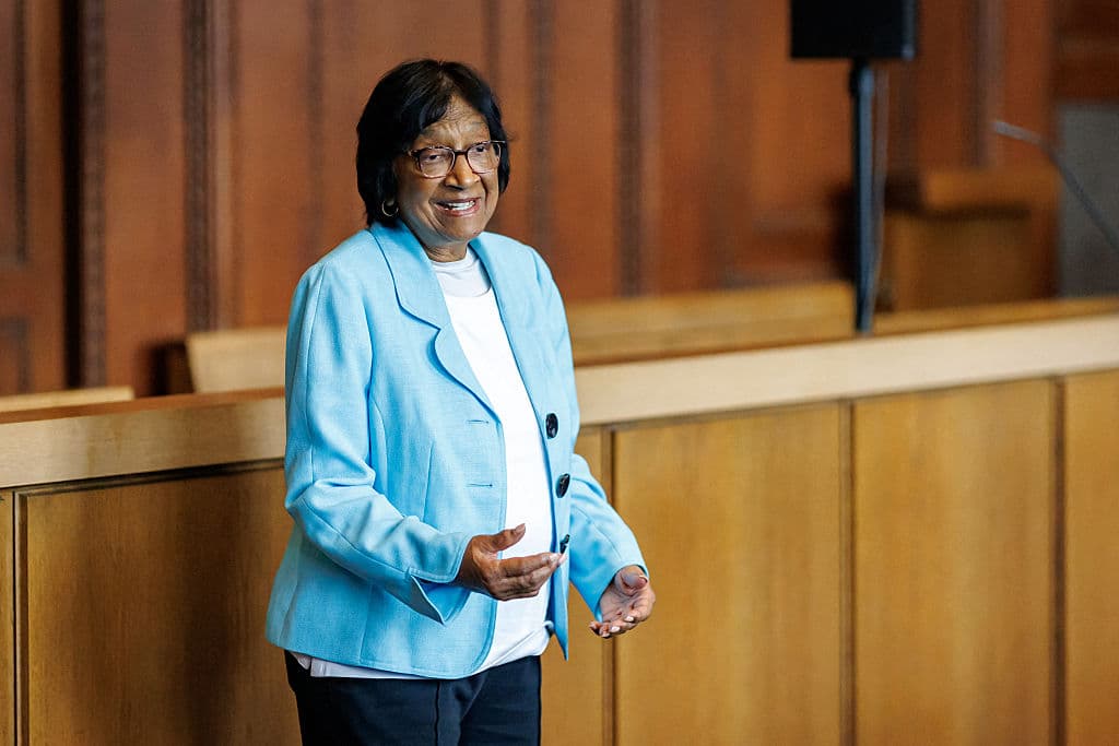 Navi Pillay speaking and gesturing while standing in a wood-paneled courtroom