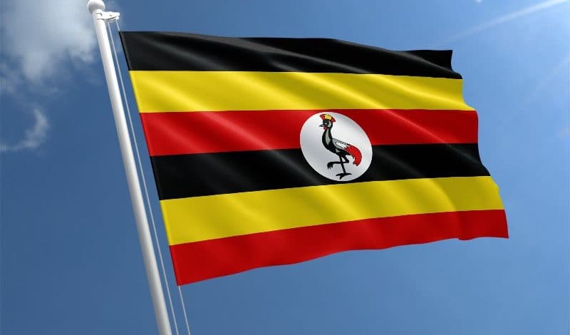 The flag of Uganda flying against a blue sky